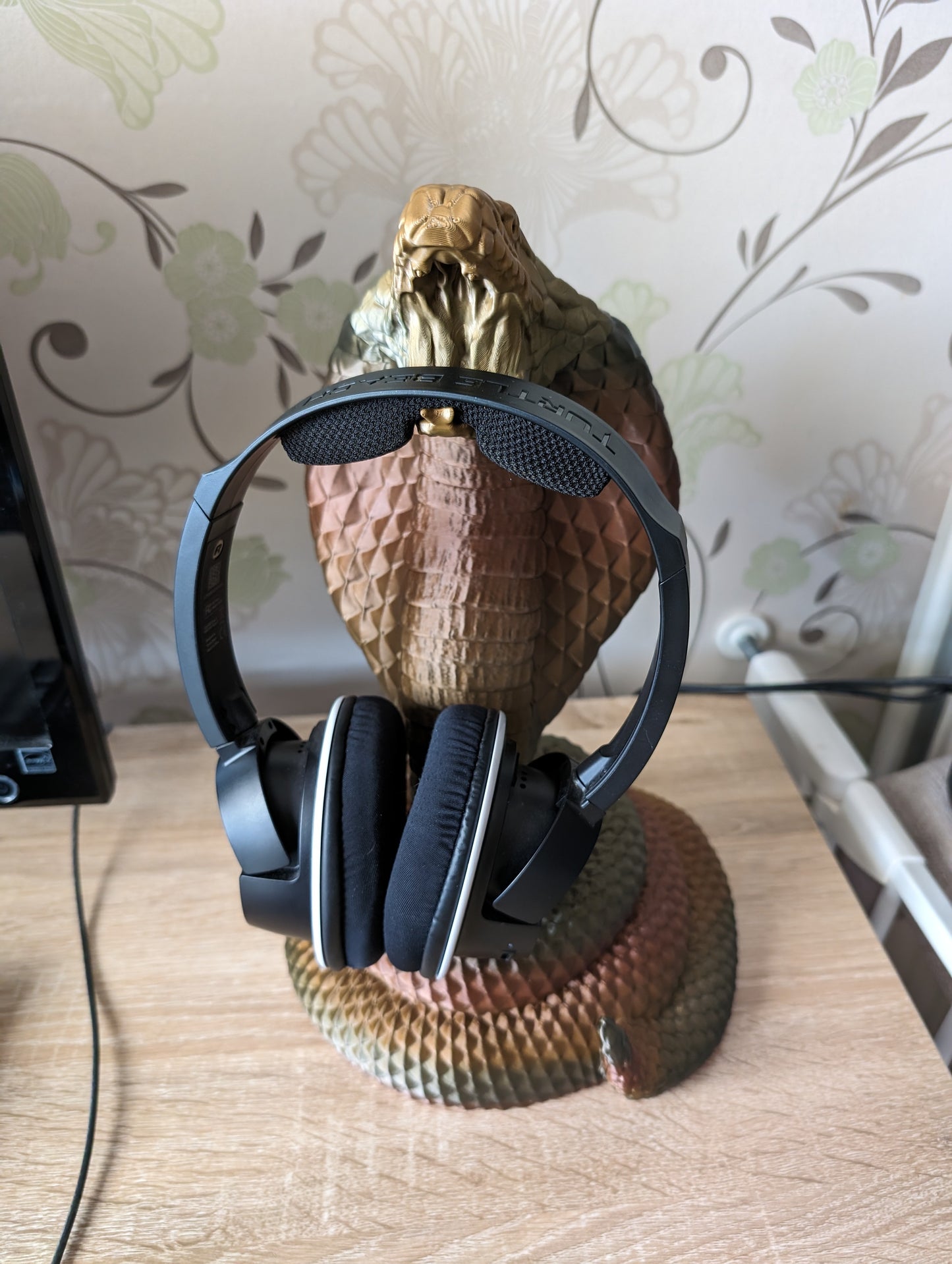 Cobra snake headphone holder on desk from a front angle