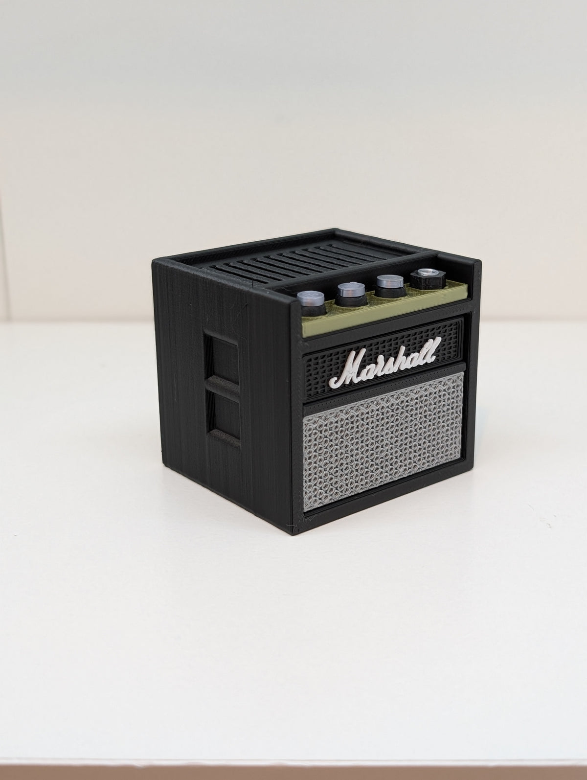 Mini guitar amp pick holder from the side, showing the vents and knobs