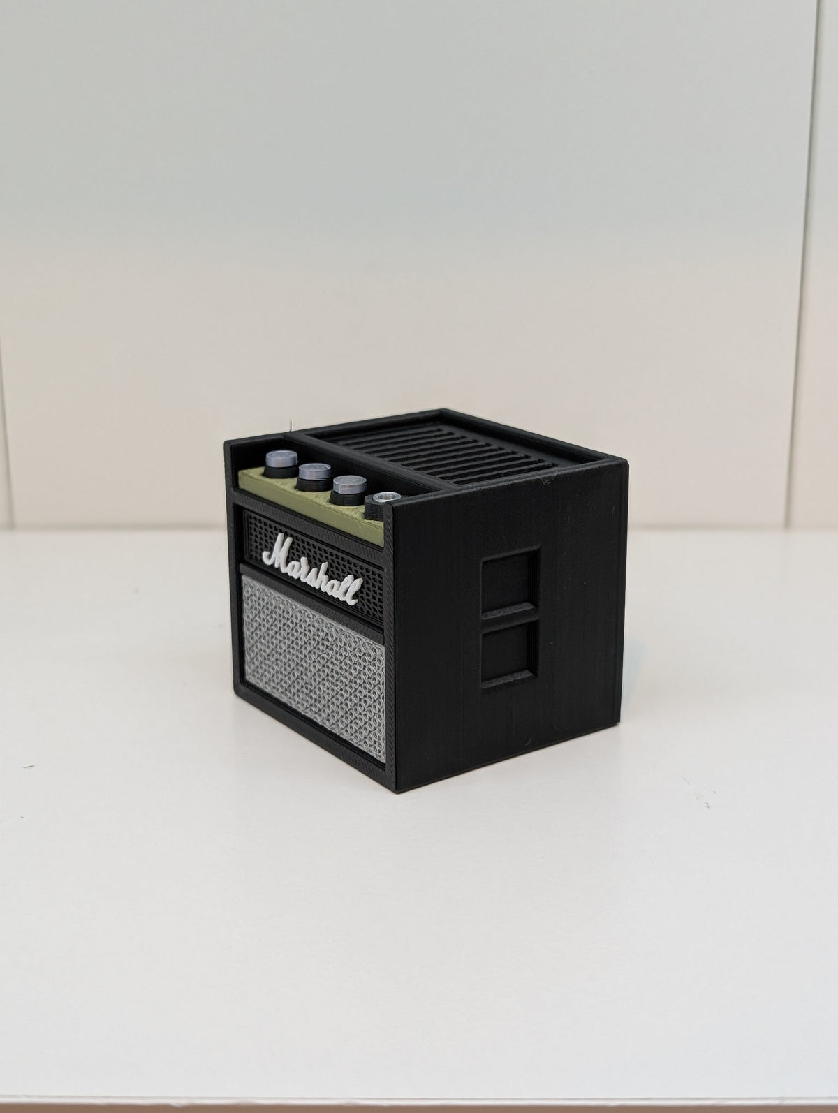 Black mini guitar amp pick holder with gold control strip and grey speaker grille