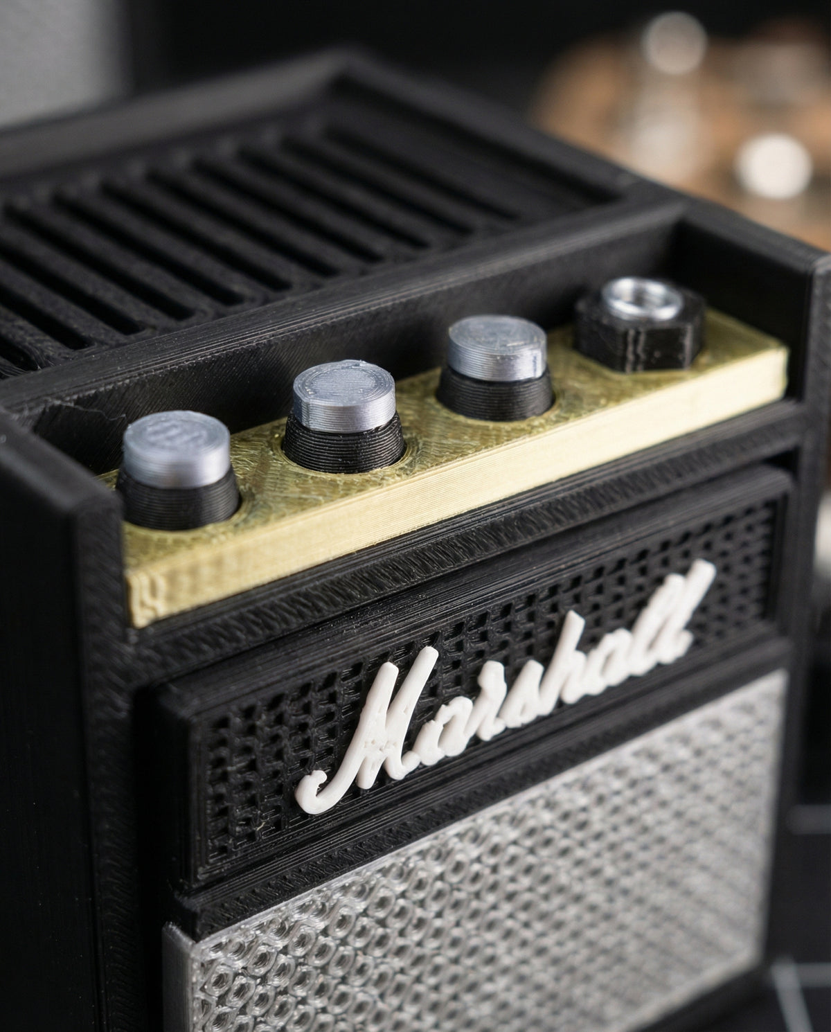 Close-up of the silver knobs, gold control strip and raised script logo