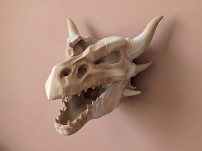 Dragon skull wall planter on a pink wall, showing the horns, teeth and open jaw