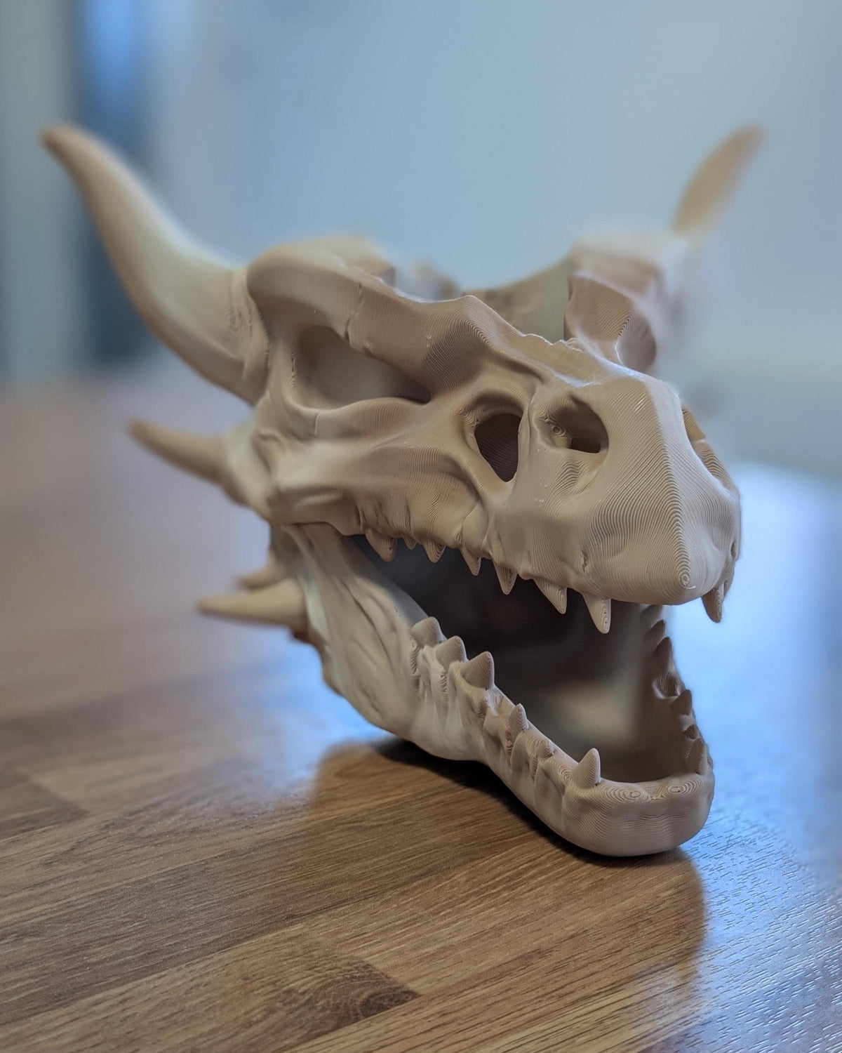 3D printed dragon skull planter on a wooden table, showing the open jaw and teeth