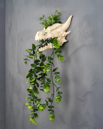 Dragon skull wall planter with artificial foliage on top and trailing from the mouth