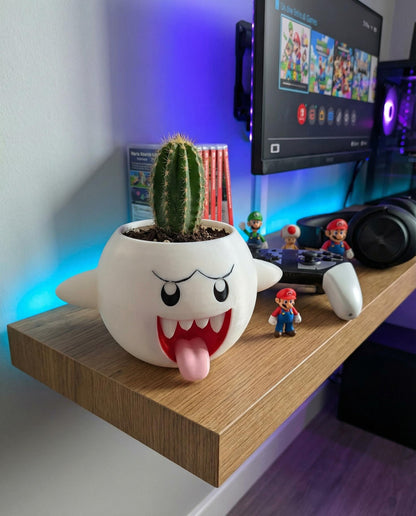 Boo planter with a cactus on a gaming desk shelf