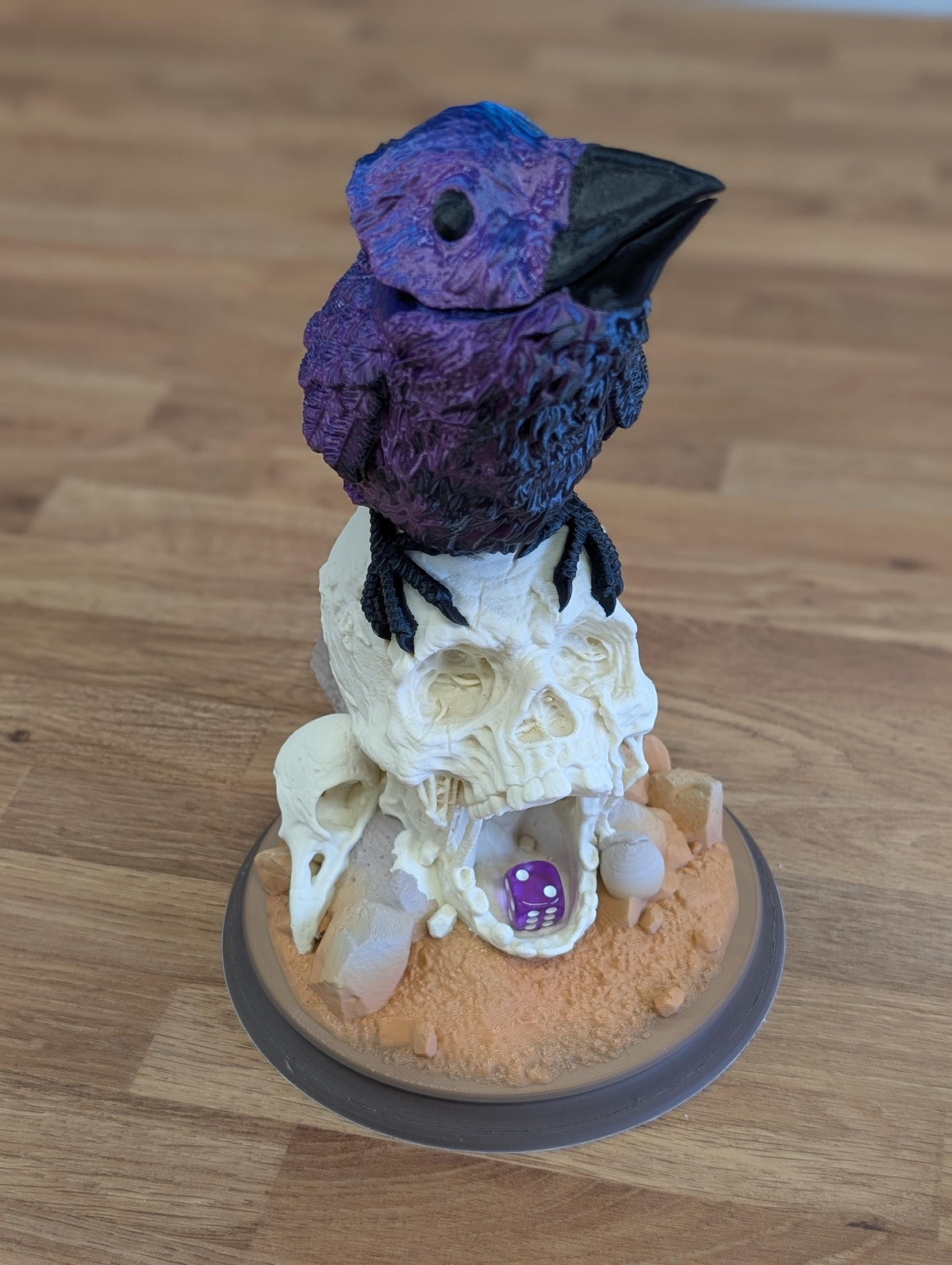 Full Colour raven dice tower from the front: blue and purple silk raven on a bone white skull